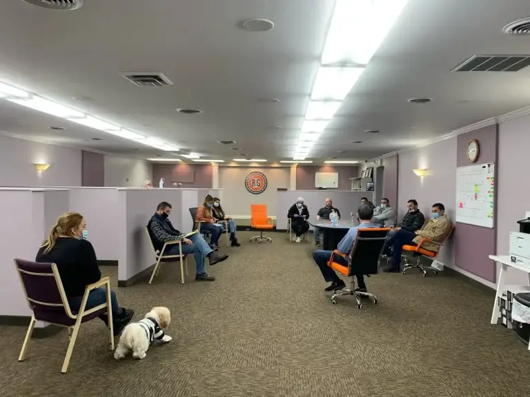 A group of people sitting in an office with their dogs.