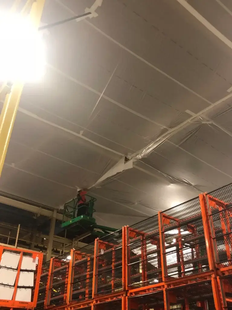 A man on a scissor lift in an industrial setting.